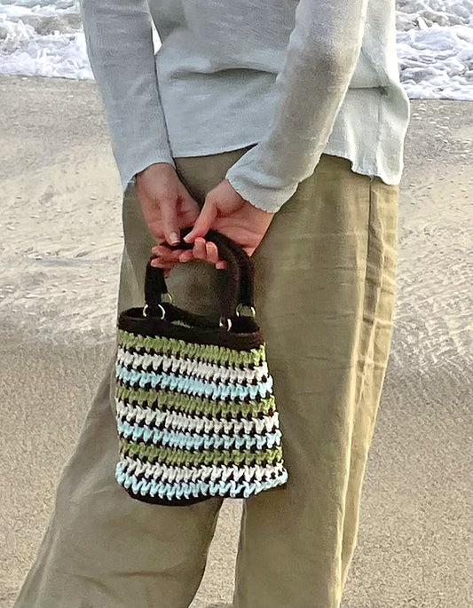 The colors of Cambria are captured in this one-of-a-kind, retro style, hand crocheted bag. Up cycled, cotton/poly blend yarn and brass ring detail to anchor the handles. Reinforced bottom to insure sturdy strength for bag contents. Bag Dimensions: 11"wide x 9"high (Handles: 6"wide x 5"high) Colors: Sky Blue, Sage Green, Shell Ivory, Rock Espresso Consciously crafted in California