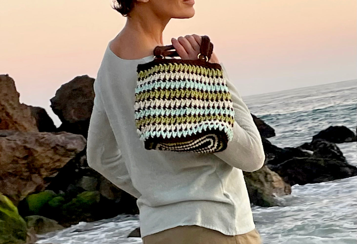 The colors of Cambria are captured in this one-of-a-kind, retro style, hand crocheted bag. Up cycled, cotton/poly blend yarn and brass ring detail to anchor the handles. Reinforced bottom to insure sturdy strength for bag contents. Bag Dimensions: 11"wide x 9"high (Handles: 6"wide x 5"high) Colors: Sky Blue, Sage Green, Shell Ivory, Rock Espresso Consciously crafted in California